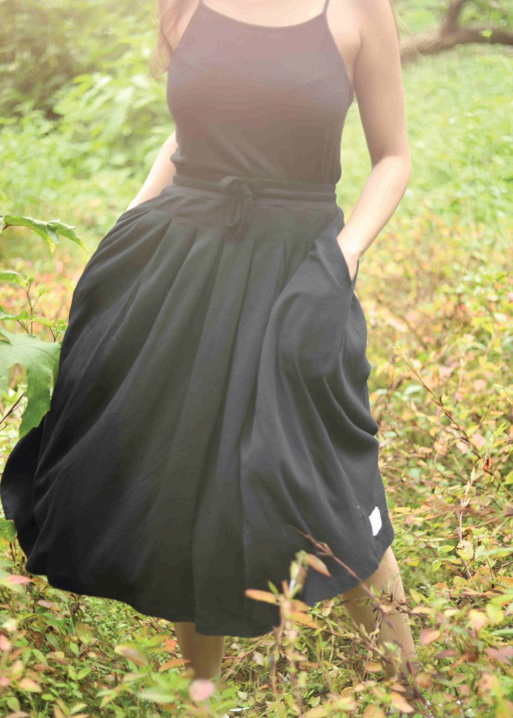 Black is a voluminous skirt with side seam pockets and an adjustable drawstring waistband.
