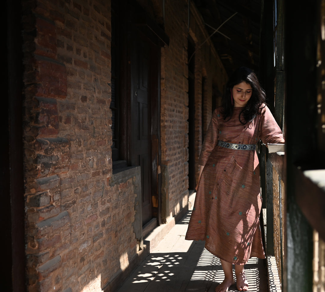 Dress comes in a multi-colour silk weave with a diagonal placket in front. It comes in hues of burnt red with light blue and yellow.