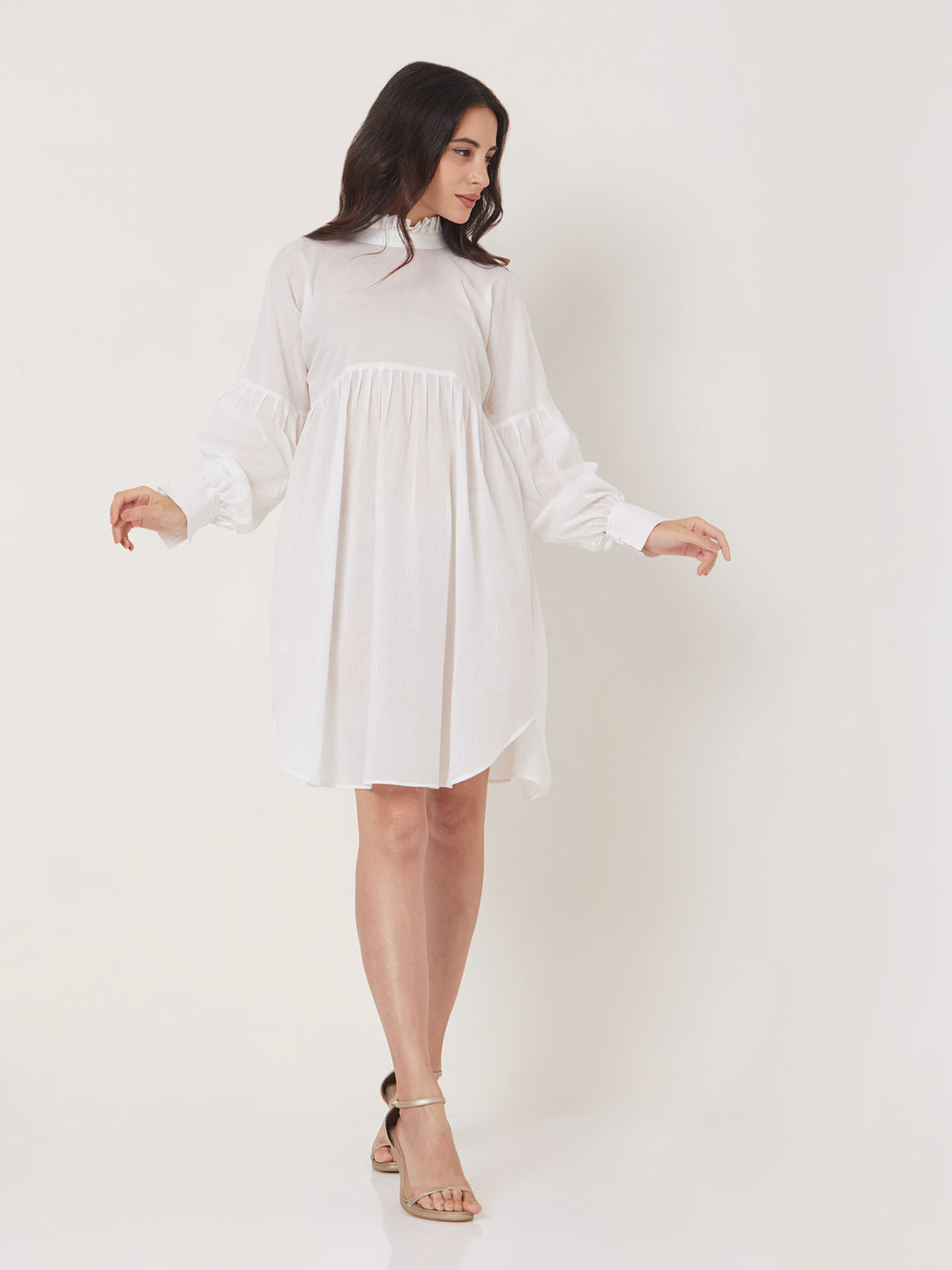 A loose short dress is unlined, knee length, has a U-shaped hemline, and a high pleated neck.