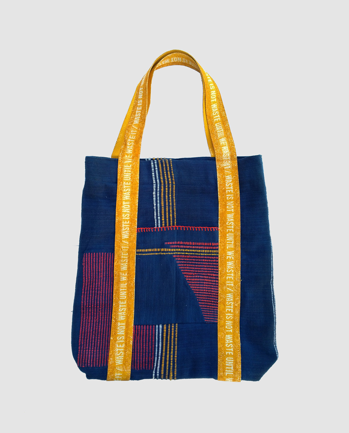 A blue handwoven shoulder bag with a magnetic button closure and two fabric handles.