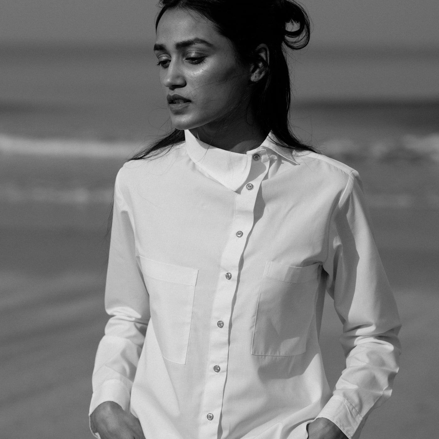 White collared upcycled shirt. It has a front button placket and an irregular hemline.