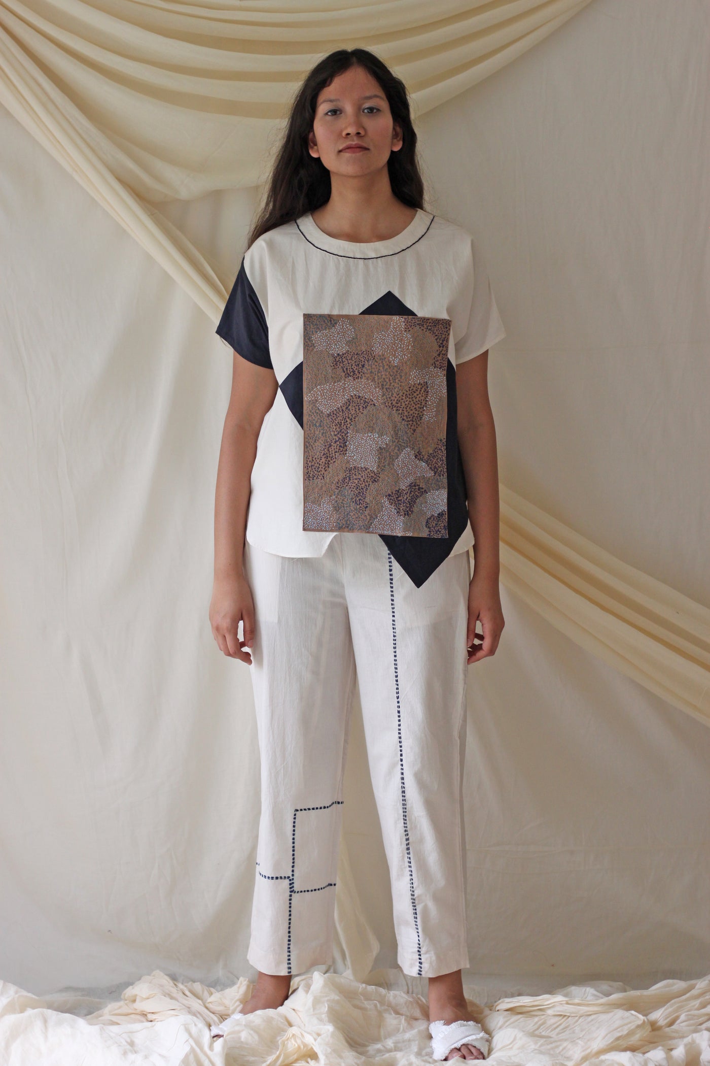 An ivory woven T-shirt with abstract embroidery and white pants