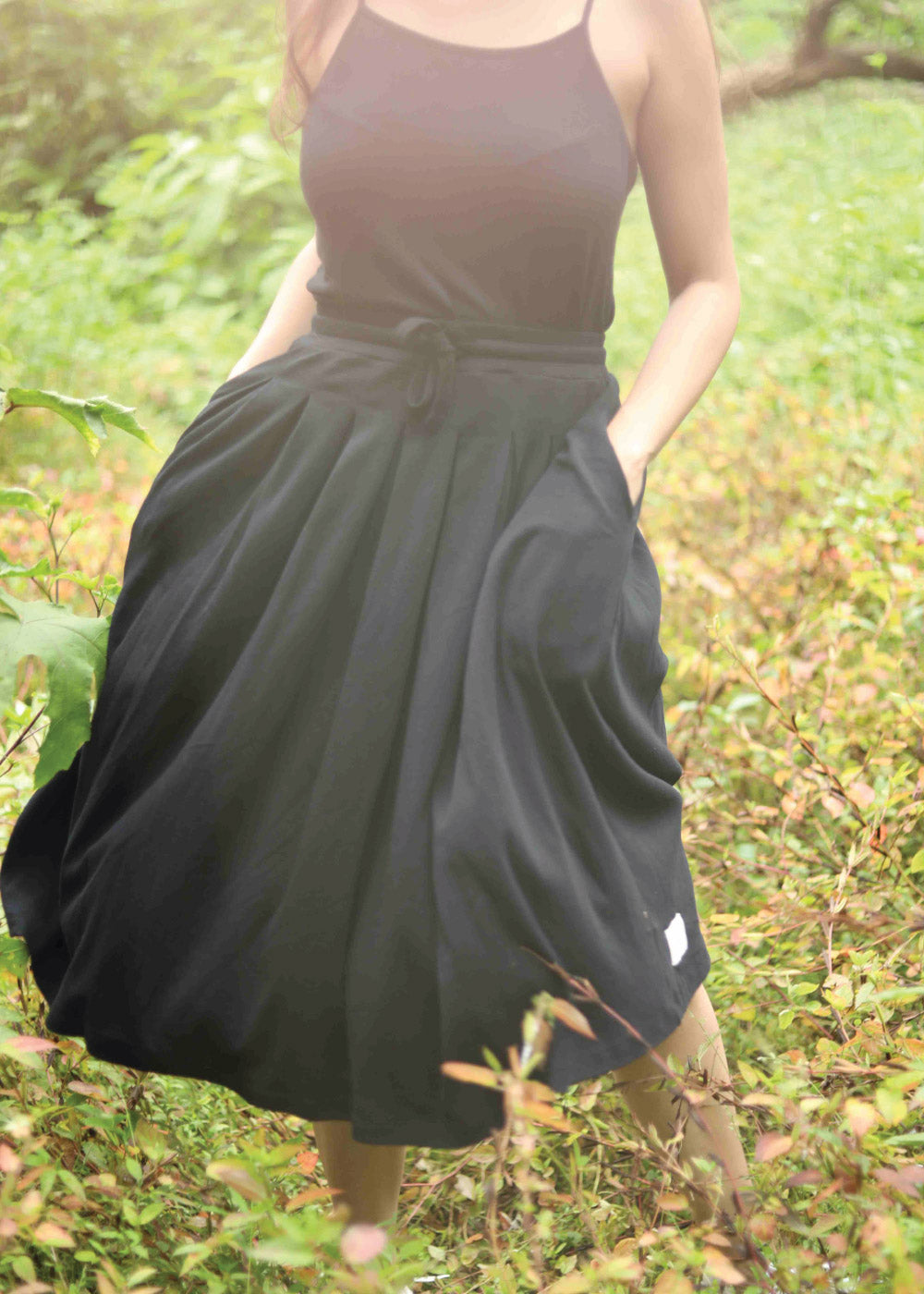 Black is a voluminous skirt with side seam pockets and an adjustable drawstring waistband.