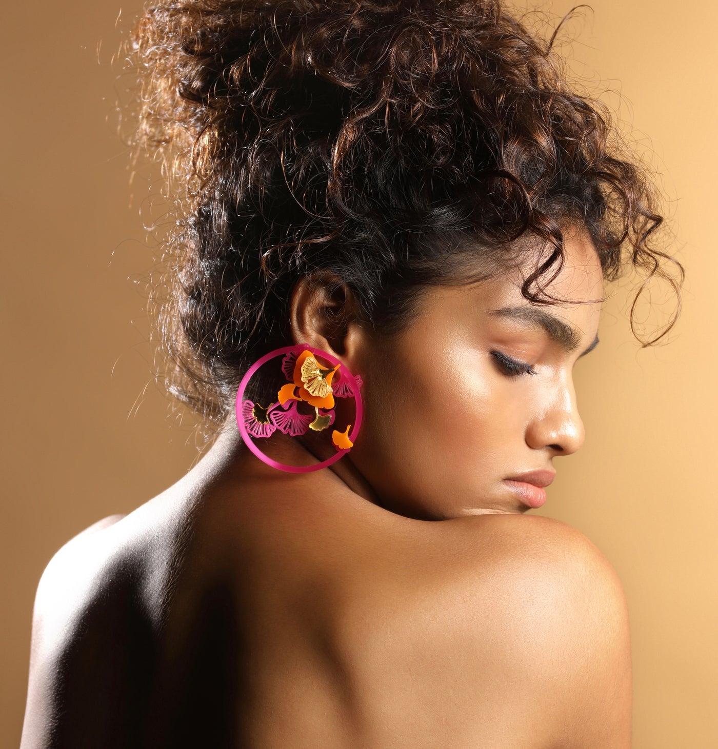 pink coloured earrings with circular border and detailed pattern in the middle