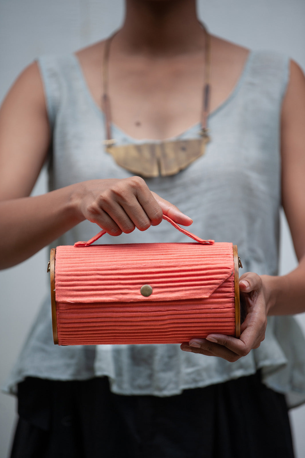 100% handcrafted round clutch comes with 1 detachable sleeve - in a solid coral hue.