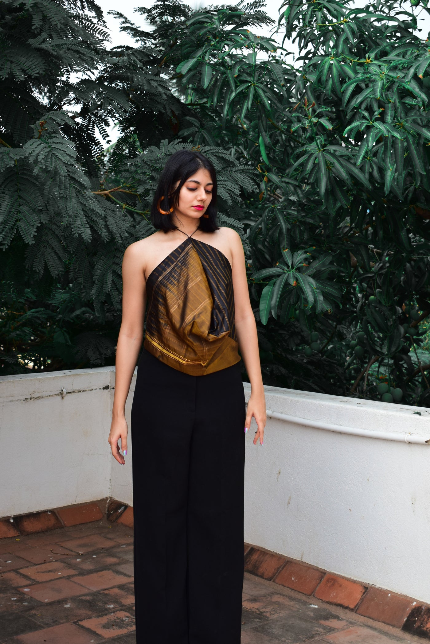 A halter neck top in dull gold and black featuring pleated detailing