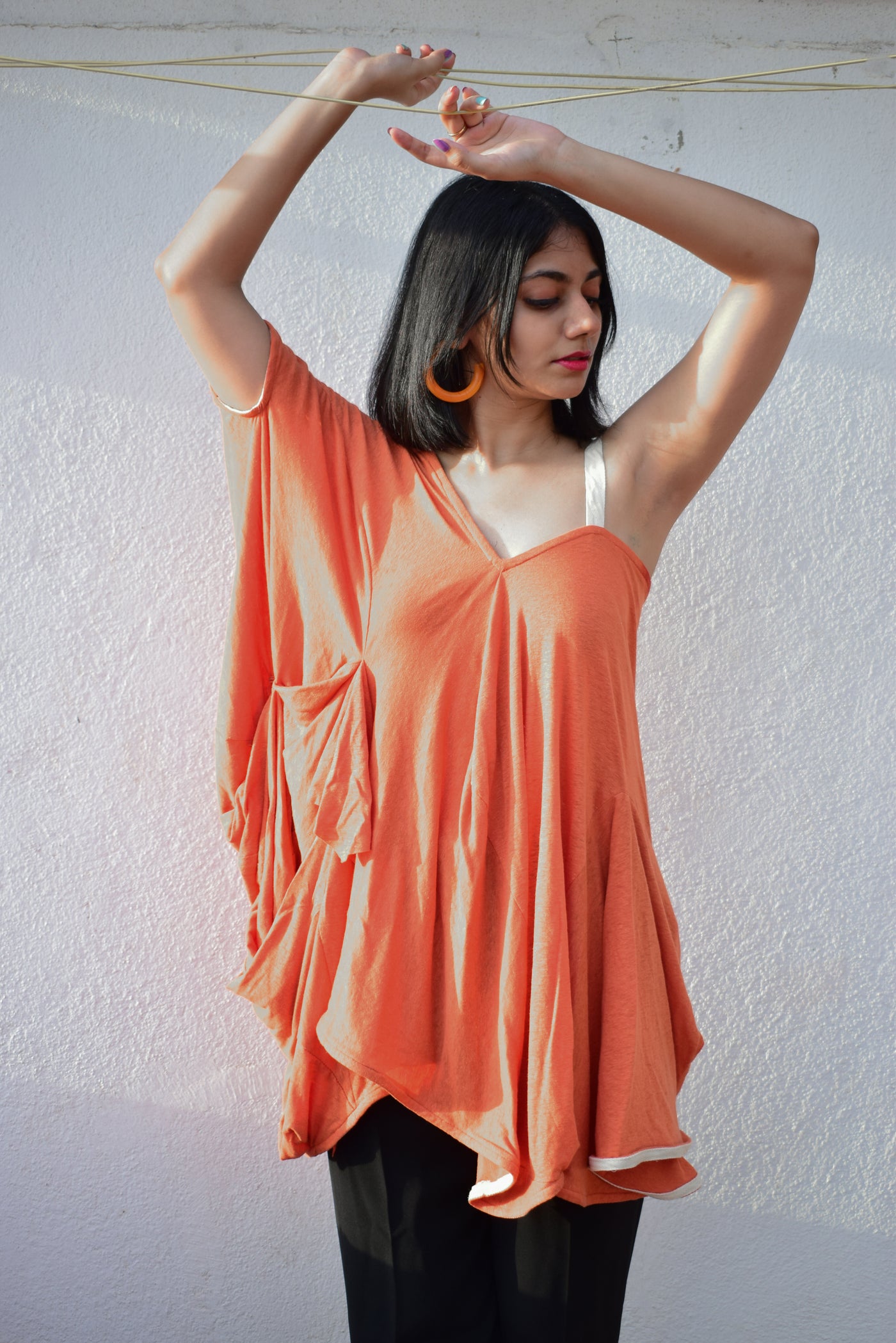 A bright Orange top with one puffed sleeve and one simple strap