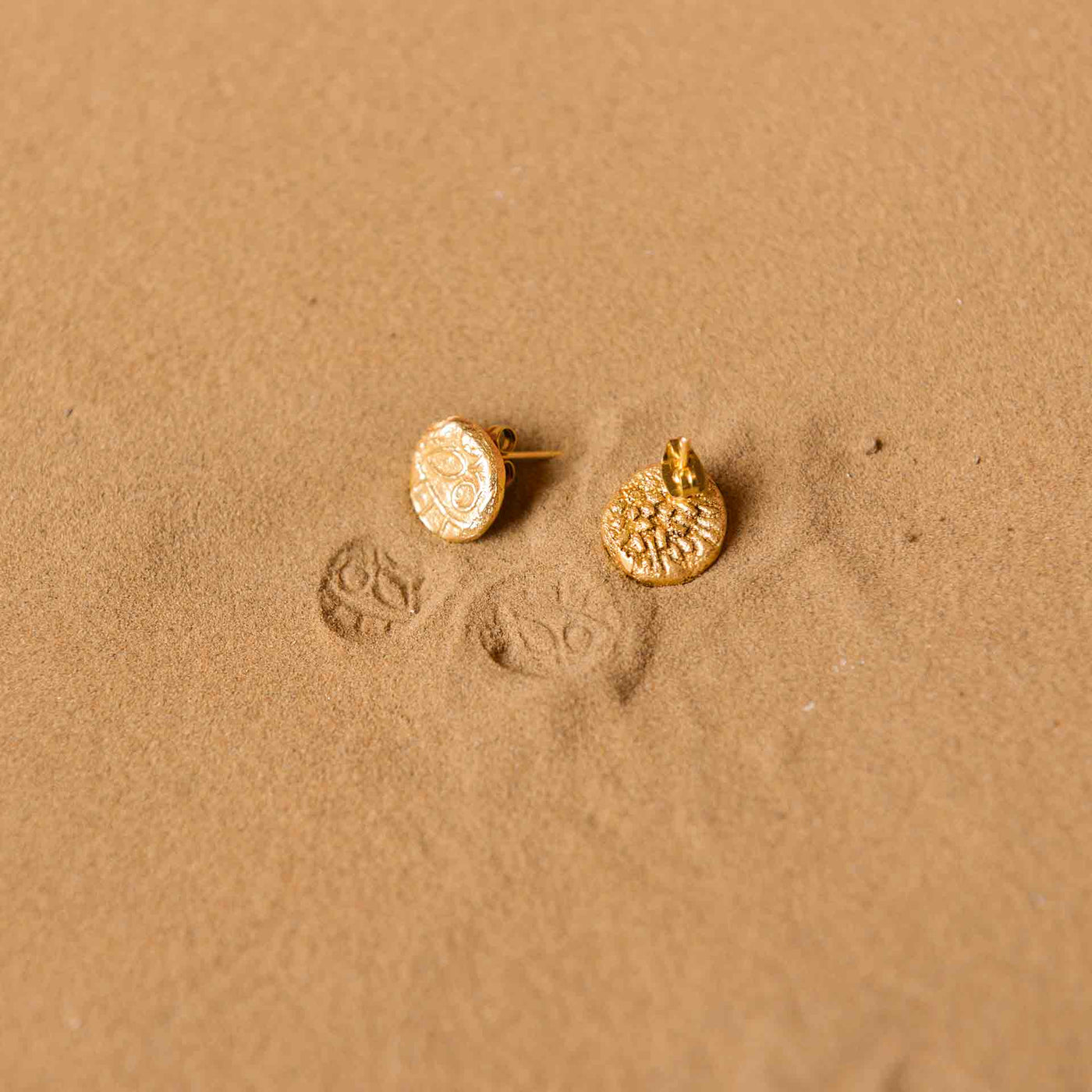 A pair of dye gold studs, which are made to resemble fossils.