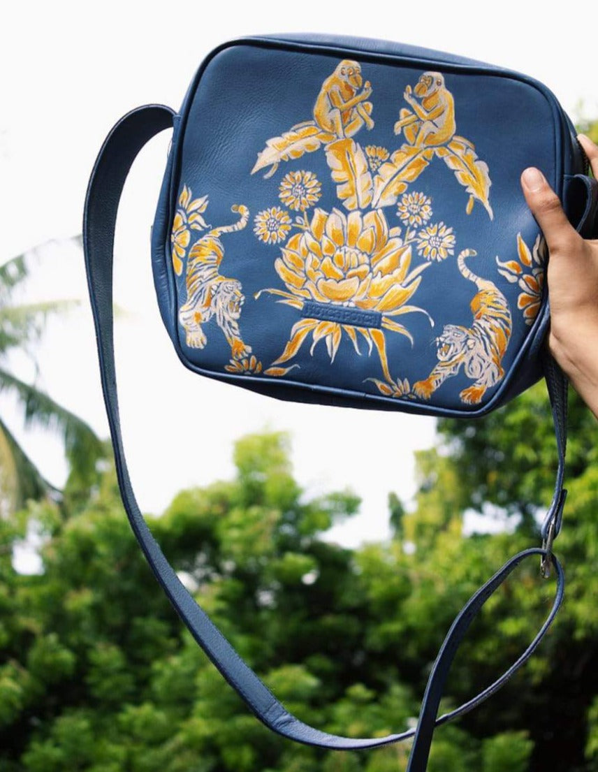 Blue sling bag with an intricate yellow nature pattern