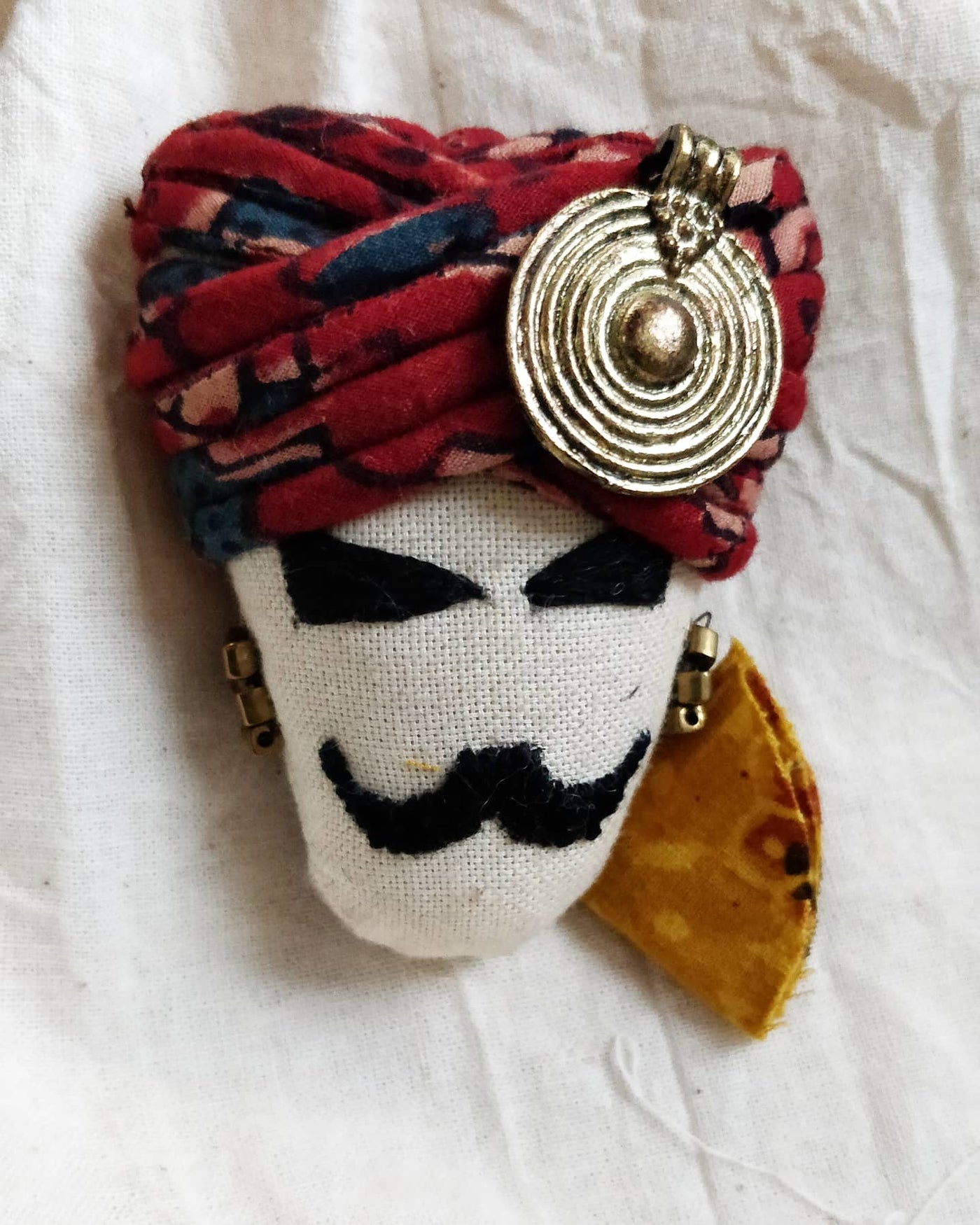 brooch with a design with white coloured face with red turban