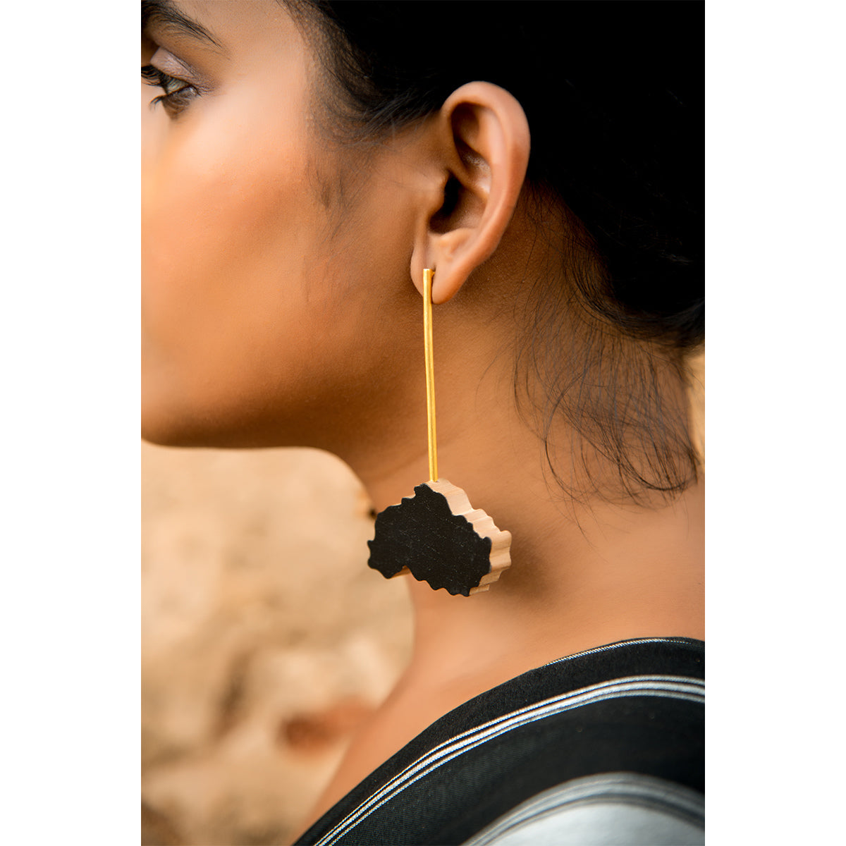 The black earrings are handcrafted using reclaimed teak wood and gold plated brass.