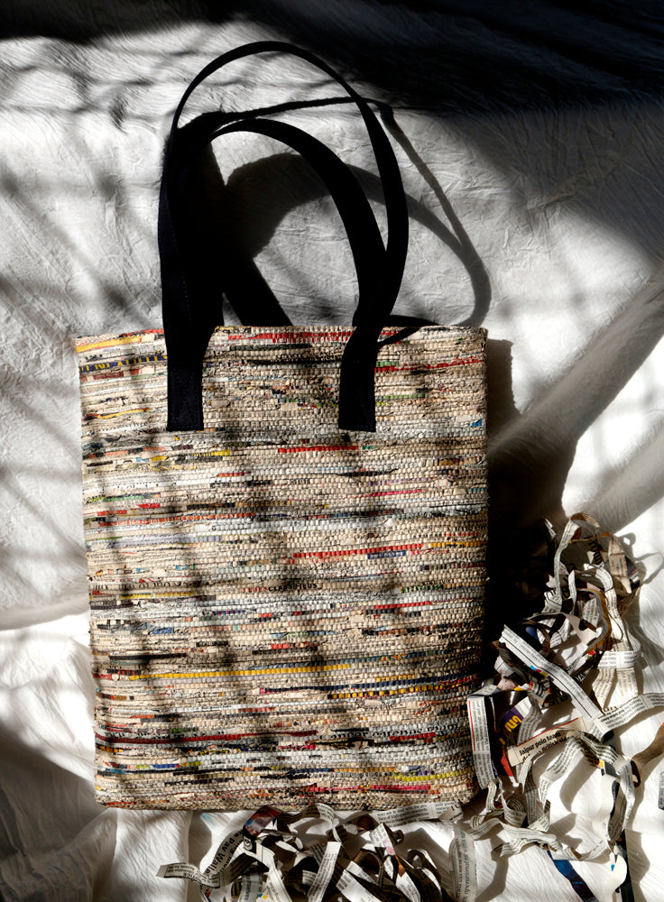 Handmade, functional tote bag made from cotton and newspaper strips with handles and a navy lining.