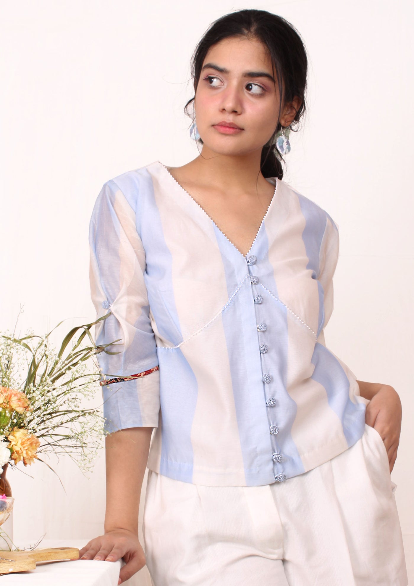 A V neck top with blue stripes, sleeve details and front opening